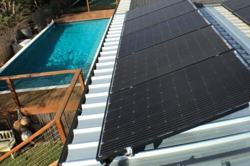 Solar pool heating panels installed on roof beside swimming pool