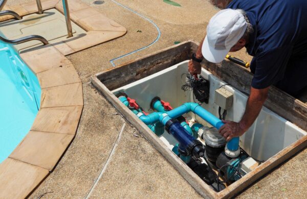 repairing-a-swimming-pool-pump Professional technician repairing a swimming pool pump during routine maintenance