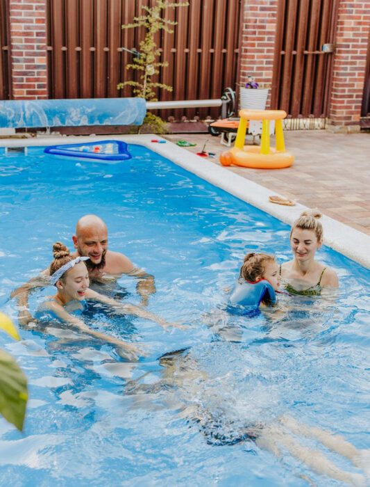 Family enjoying a clean, healthy swimming pool maintained with professional pool maintenance services in Melbourne