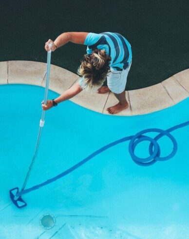 Pool technician cleaning a residential swimming pool in Burnside Heights