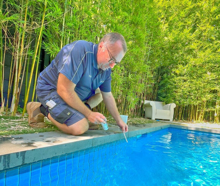 Pool technician professionally testing swimming pool water during routine pool cleaning and maintenance service in Melbourne