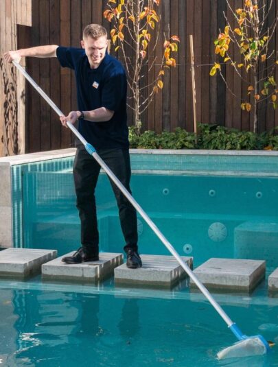 Pool technician cleaning a residential swimming pool