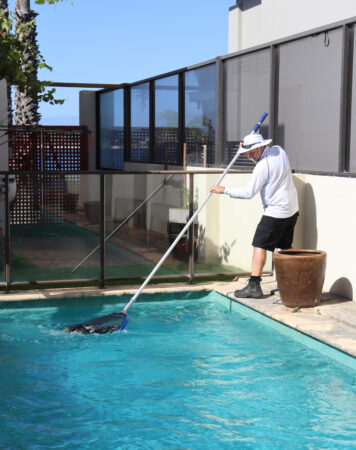 Pool technician cleaning a residential swimming pool in Greenvale