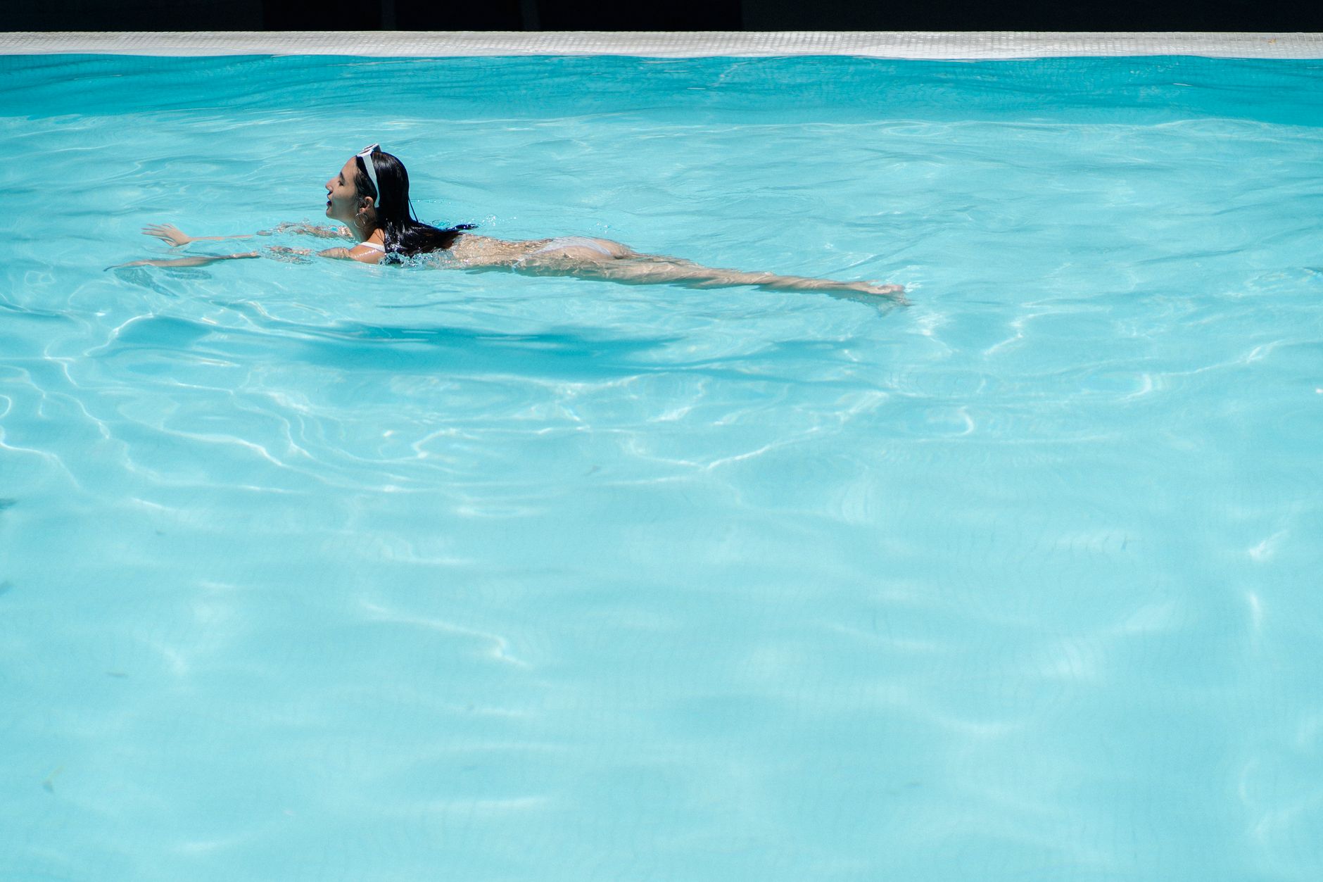 Side view full body of female tourist swimming in pool with crystal clear water at resort, how to recover a green pool safely