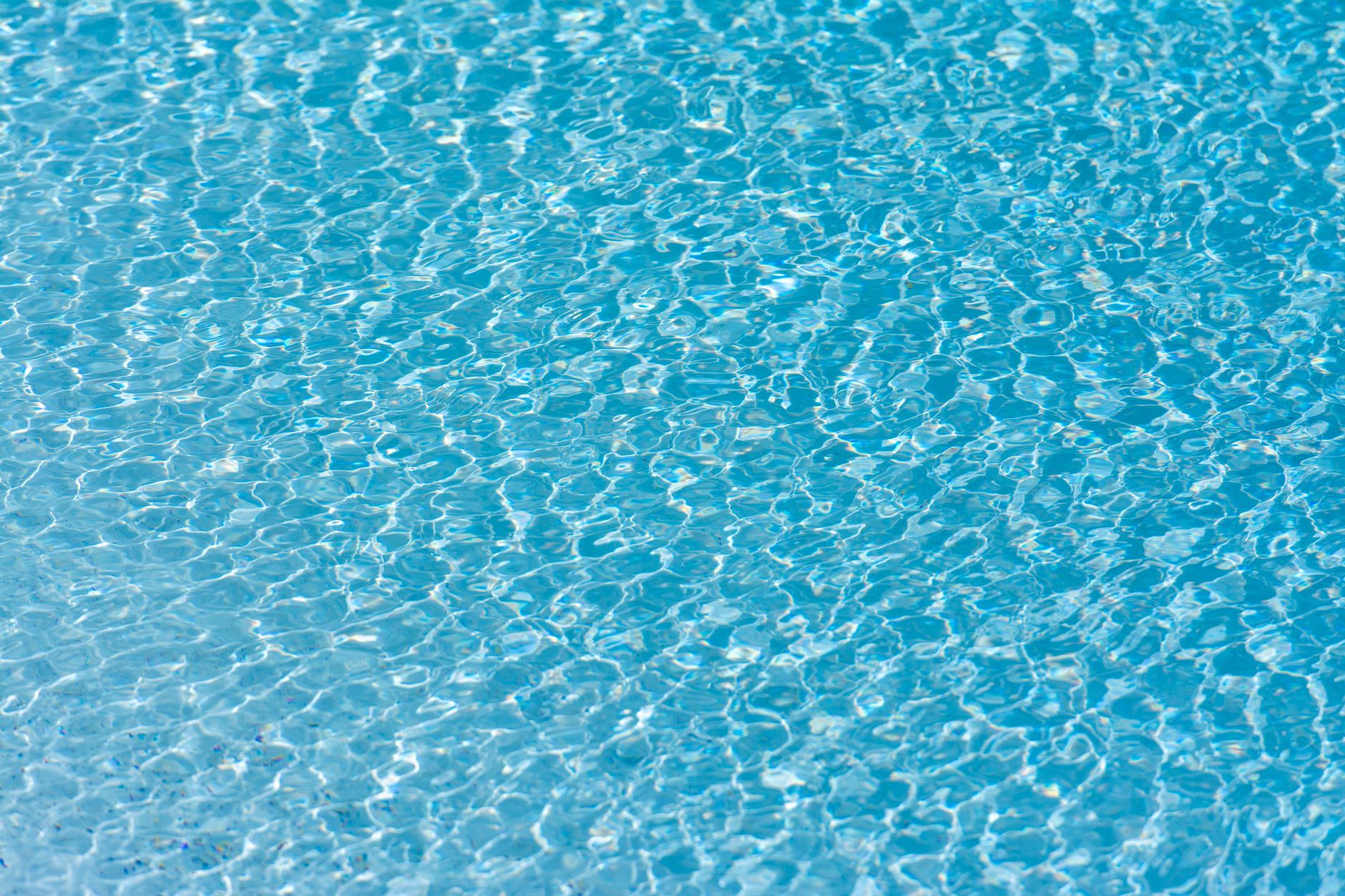 Texture and pattern of rippling turquoise water in a swimming pool with clear reflections.