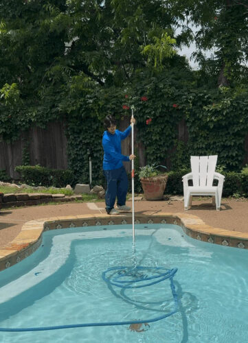 Pool technician cleaning a residential swimming pool in Hillside